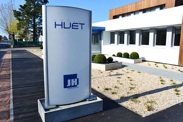 Totem extérieur blanc et bleu avec logo Huet devant bâtiment design
